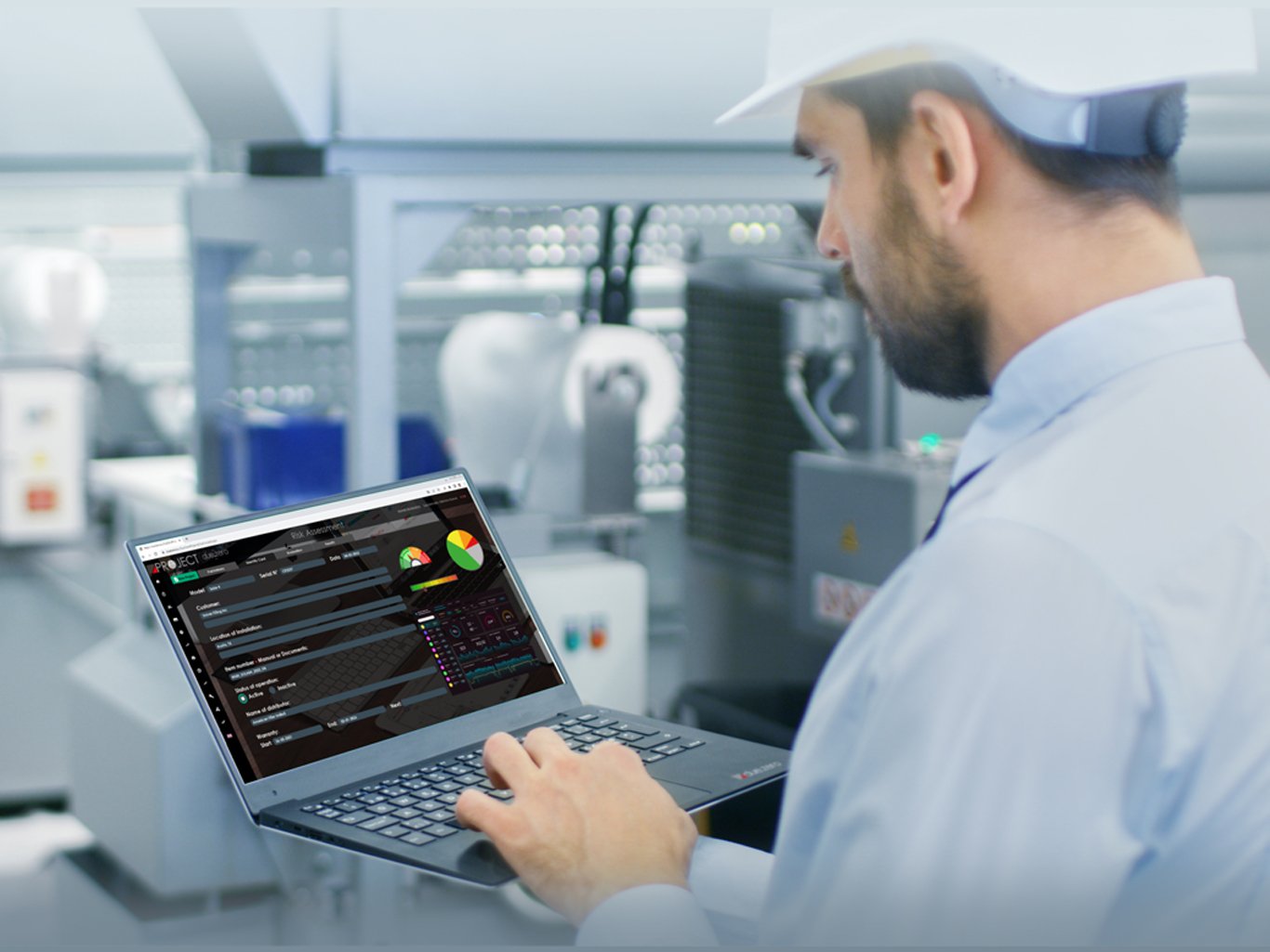 Tecnico con elmetto protettivo in stabilimento operativo che utilizza un computer portatile per il Risk Assessment.